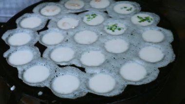 Tedarikçinin Kanom krok 'un üzerine çeşitli malzemeler koyduğu görüntüler. Lezzetli bir Tayland hindistan cevizi sütü krepi.