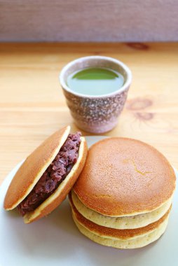 Arkaplanda bir fincan sıcak kibrit yeşil çaylı Dorayaki Kekleri