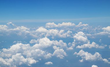 Gökyüzünde süzülen beyaz bulutlar bulutların üzerinde uçarken uçaktan görünüyor.