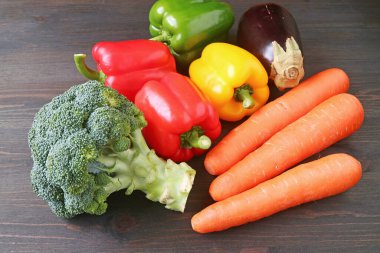 Siyah ahşap arka plana saçılmış çeşitli taze sebzeler yığını.