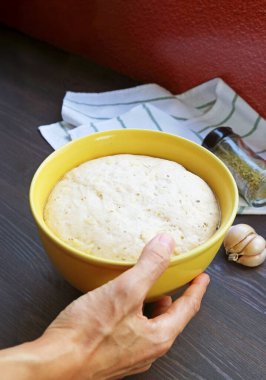 Adamın eli mutfak masasına bir kase kabarık hamur koyuyor.