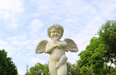 Bahçedeki sevimli aşk tanrısı heykeli yumuşak bulutlu gökyüzüne karşı