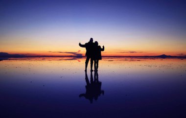 Mutlu bir çiftin silueti, Uyuni Tuz Düzlükleri 'nin günbatımı gökyüzüne, Bolivya' ya, Güney Amerika 'ya karşı fantastik ayna efektine çarpıyor.