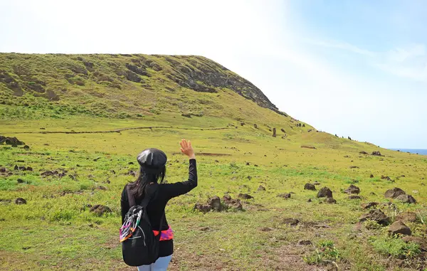 Paskalya Adası, Şili, Güney Amerika 'daki ünlü Moai heykellerinin taş ocağı etkileyici Rano Raraku yanardağına el sallayan kadın ziyaretçi.