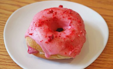 Ağız sulandıran çilek, ahududu kremalı, ahşap masaya dolgulu donut.