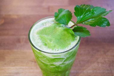 Ağız sulandırıcı ev yapımı sebze suyu ve ahşap masa üzerinde beyaz palamut otu.