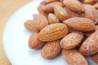 Badem çekirdeği dolu beyaz tabak Tahta Masa 'da izole edildi