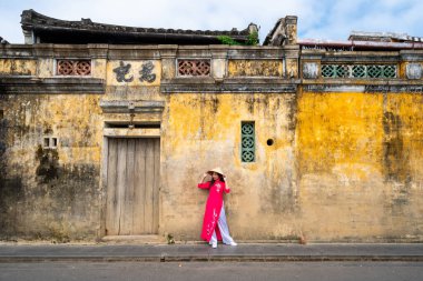 Young female tourist in Vietnamese traditional dress walking at Hoi An Ancient town in Vietnam