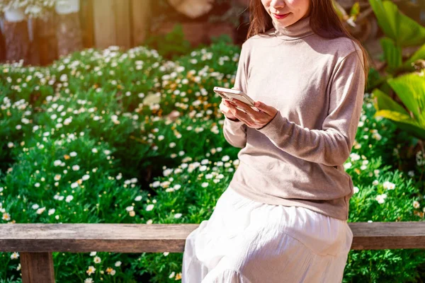 Young female using mobile phone and relaxing in the garden, Modern lifestyle