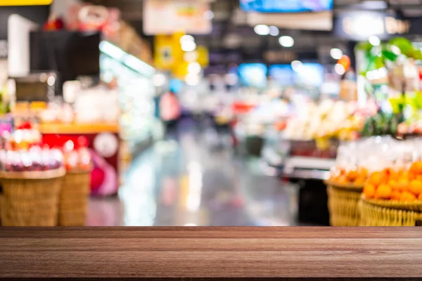 概要空の木製テーブルスペースのあるモールでのスーパーマーケット食料品店のぼやけたイメージ — ストック写真