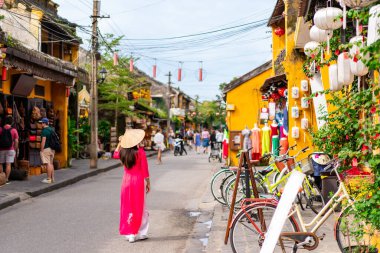 Young female tourist in Vietnamese traditional dress walking at Hoi An Ancient town in Vietnam