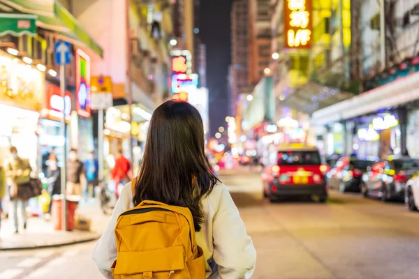 Hong Kong 'daki Mong Kok gece pazarında yürüyen genç bir kadın gezgin.