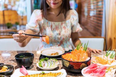 Japon restoranında saşimi yiyen Asyalı genç bir kadın.