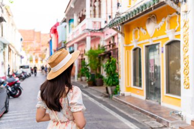 Tayland 'ın eski Phuket kasabasında yürüyen genç bir kadın gezgin.