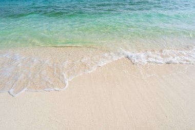 Dalgalı, şeffaf deniz, yaz tatili ve arka planda fotokopi alanı olan güzel tropik beyaz kumsal.