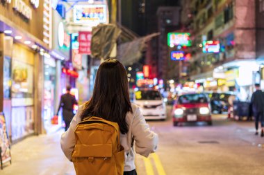 Hong Kong 'daki Mong Kok gece pazarında yürüyen genç bir kadın gezgin.
