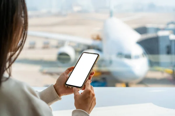 Junge Asiatin Benutzt Smartphone Während Sie Flughafen Auf Ihren Flug lizenzfreie Stockbilder