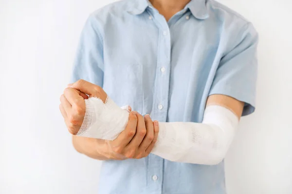 Young man with gauze bandage wrapped around injury hand on white background