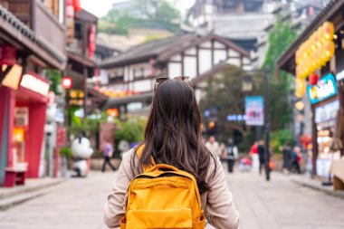 Çin 'in Chongqing kentindeki Ciqikou antik kasabasında yürüyen genç bir bayan turist.
