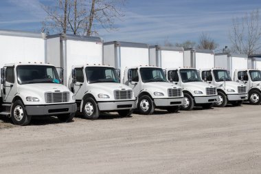 Indianapolis - Circa April 2023: Freightliner Semi Tractor Trailer Big Rig Trucks Lined up for sale. Freightliner is owned by Daimler. clipart