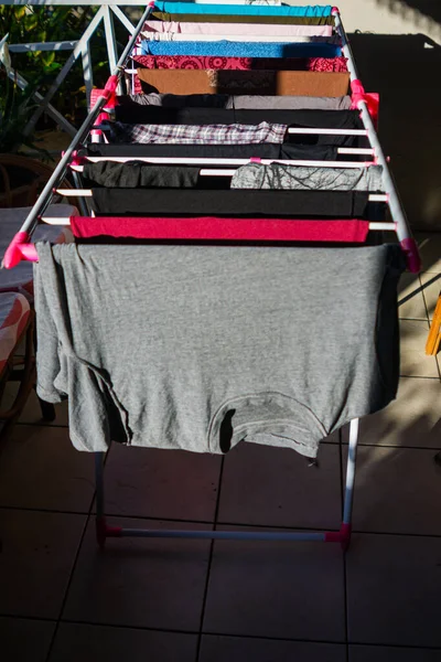 Washed clothes left to dry on a plastic rack in the sun