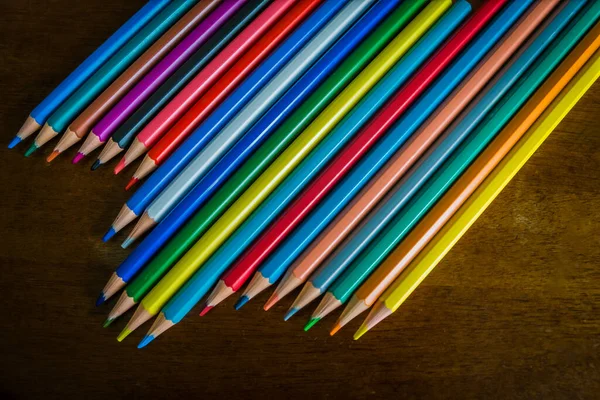 Set of multi-coloured lead pencils on a wooden school desk