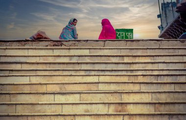 Pushkar, Hindistan, Şubat 1999 - Sırasıyla mavi ve pembe sari giymiş iki Hintli kadın, merdivenlerde halka açık bir alanda konuşuyorlar