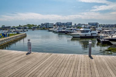 05AUG2024, Friday Harbour,Ontario, Canada - Pleasure boats moored in the marina between luxury houses on the waterfront clipart