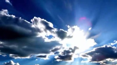 Hızlı hareket eden bulutların arasından geçen bir güneş ve güneş ışığı. Mavi gökyüzü