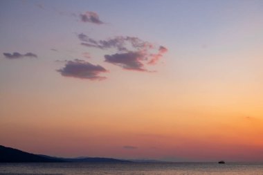 Gün batımında gökyüzü maviden kırmızıya dönerken bulutlar beliriyor.