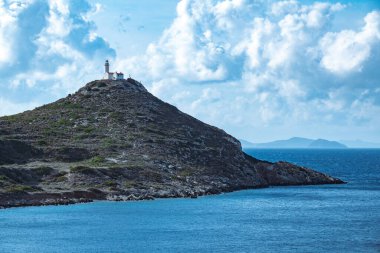 Beyaz duvarları ve açık gökyüzünün altında kırmızı çatılı Rocky Hilltop deniz feneri.