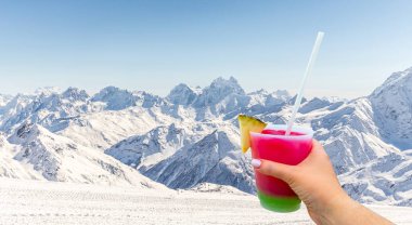 Mountains landscape with Hand holding a glass with cocktail and straw, Caucasus Russia