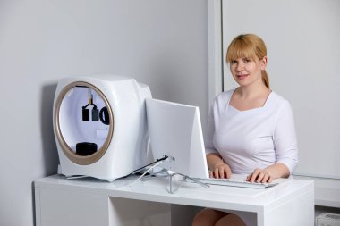 Smiling young female doctor working with her computer in the consultation in medical clinic