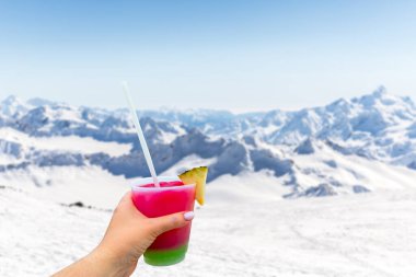 Mountains landscape with Hand holding a glass with cocktail and straw, Caucasus Russia