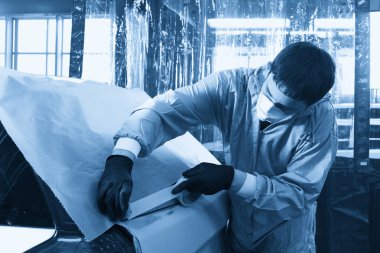 Oto tamir servisinde boyamadan önce araba kaplayan tamirci