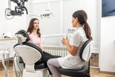 Female dentist explaining patient treatment during appointment in dental clinic