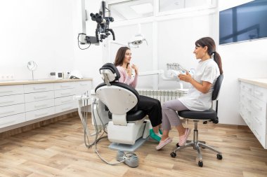 Female dentist explaining patient treatment during appointment in dental clinic