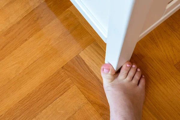 Woman hit furniture with big toe at home. Injury of foot