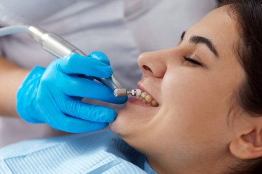 Modern diş kliniğinde dişlerini cilalatan genç bir kadın.