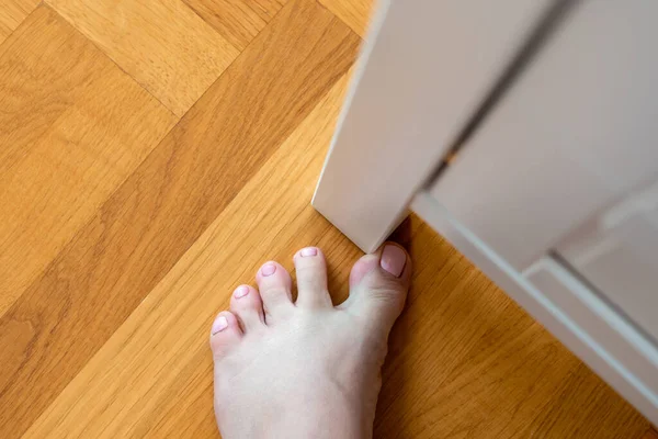 Woman hit furniture with big toe at home. Injury of foot