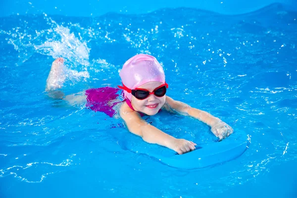 Uśmiechnięta Dziewczynka Uczy Się Pływać Krytym Basenie Trzepoczącym Deską Podczas — Zdjęcie stockowe