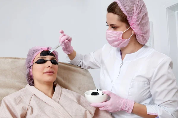 Cosmetologist Applying Black Mask Face Beautiful Woman Carbon Peeling Beauty — Zdjęcie stockowe