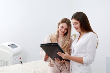 Profesyonel kozmetikçi ve bir müşteri estetik kozmetik kliniğinde prosedürden önce evrakları imzalıyorlar