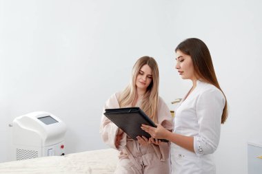 Profesyonel kozmetikçi ve bir müşteri estetik kozmetik kliniğinde prosedürden önce evrakları imzalıyorlar