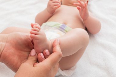 Rahatlatıcı bir ortamda, anne dikkatli bir şekilde bebeğine masaj yapar.