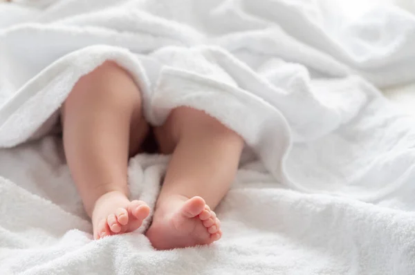 婴儿的小脚和小腿出现在柔软的白色毛巾的柔软覆盖下 流露出洗浴后的宁静 — 图库照片#