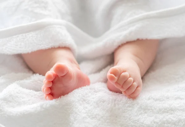 洗了个舒服的澡之后 婴儿的脚和腿在白色毛巾的柔和保护下隐约出现了 — 图库照片#
