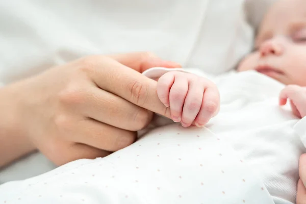 特写展示了正在熟睡的新生儿牵着母亲的手 表现出天生的联系和保护 — 图库照片#