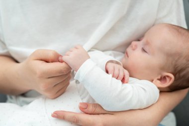 Yeni doğan bebek, hassas bir anda, annesinin parmağını tutar ve derin, konuşulmamış bir bağlantıyı vurgular.