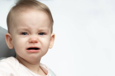 Bebek sandalyede ağlıyor, yanaklarından gözyaşları akıyor.